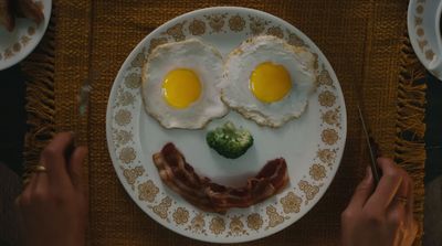 a plate with eggs, bacon, and broccoli on it