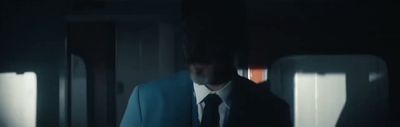a man in a suit and tie standing in a dark room