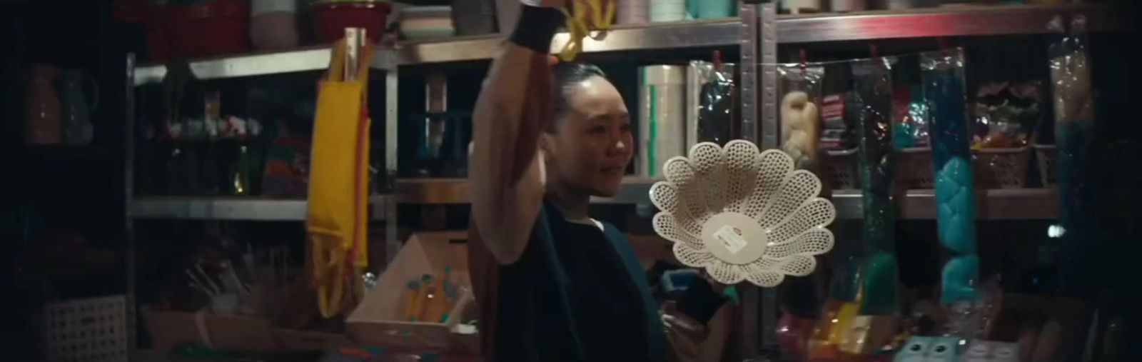 a man holding a fan in a room full of books