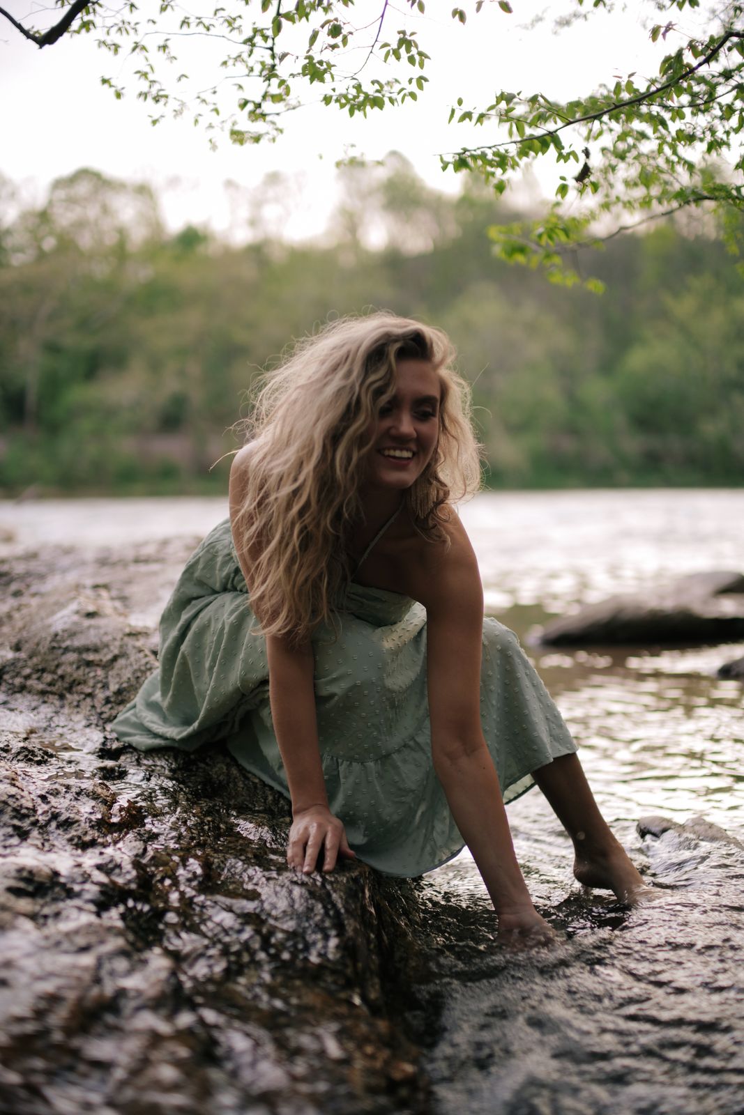 a woman sitting on a rock in the water