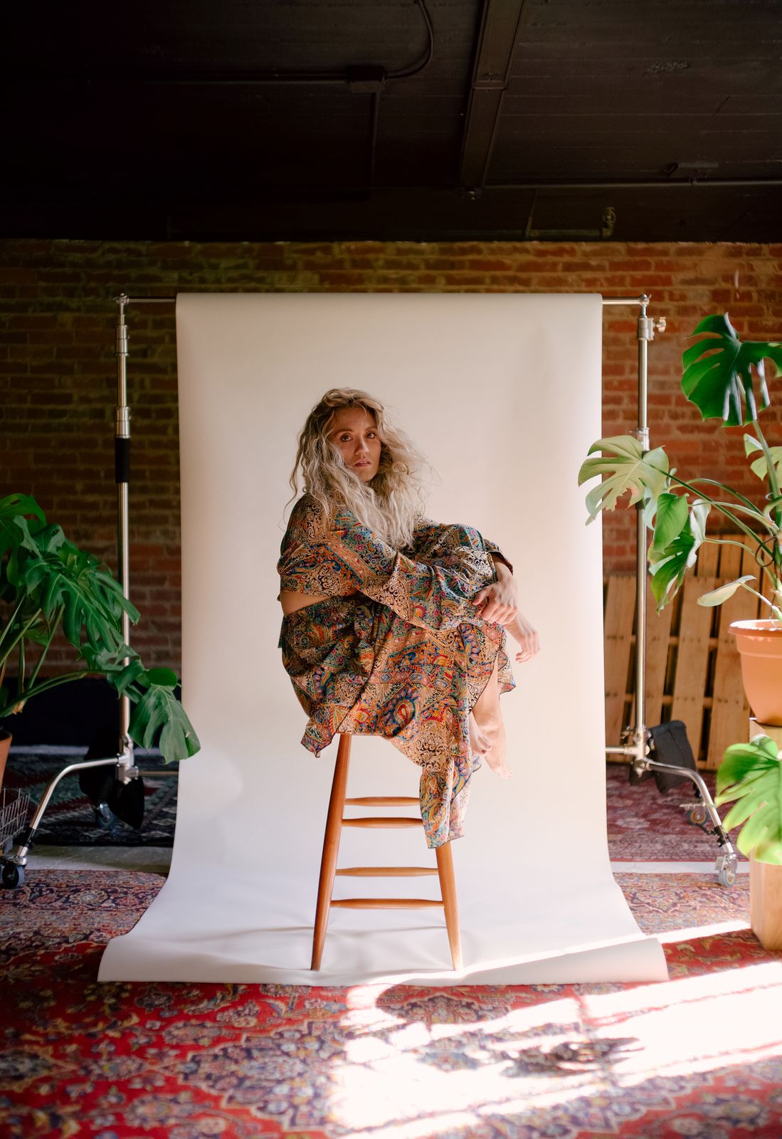 a woman sitting on a ladder in front of a white backdrop