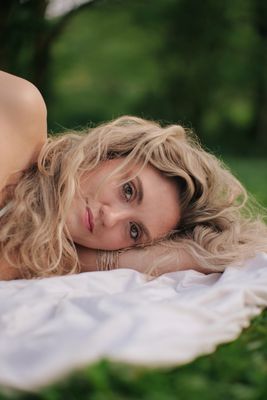 a woman laying on top of a white blanket