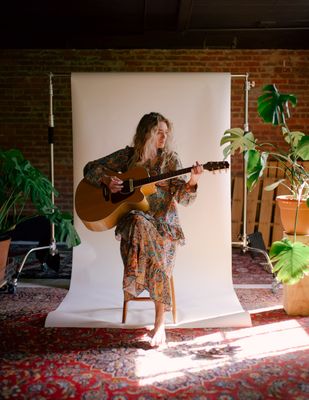 a woman sitting on a chair playing a guitar