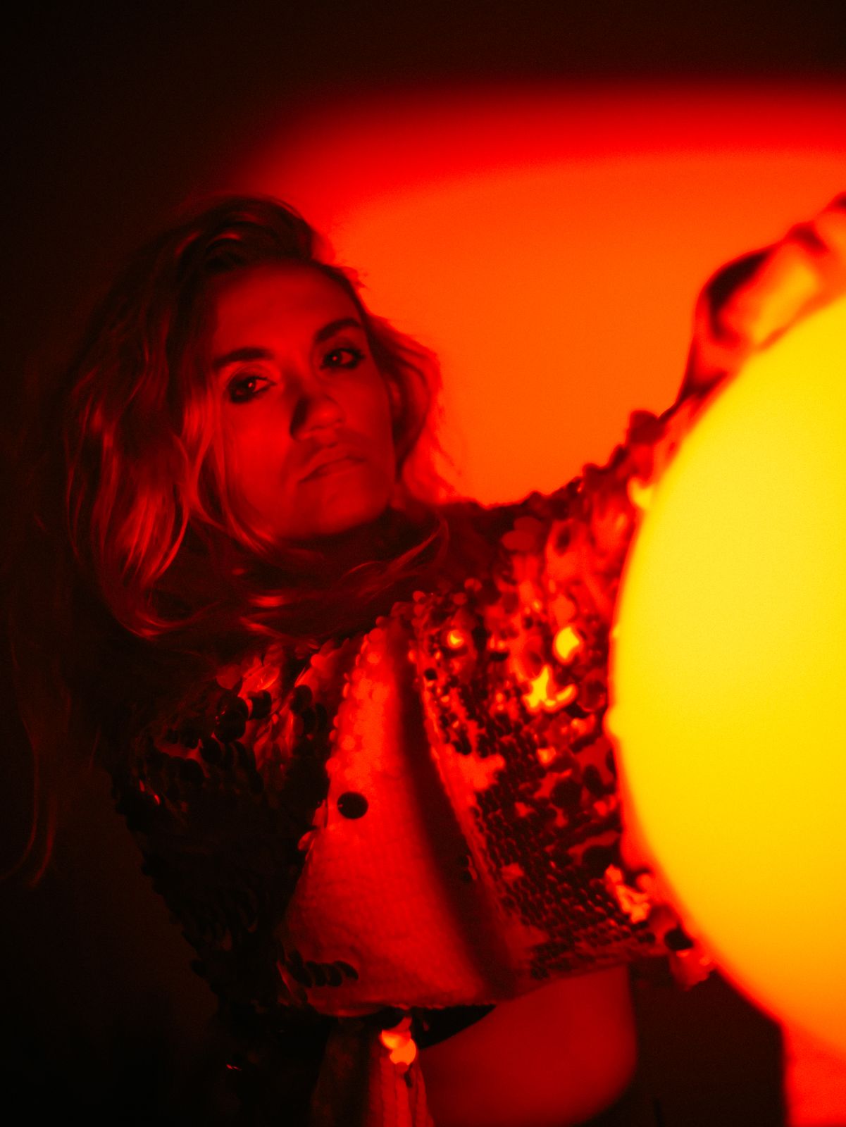 a woman holding a yellow ball in a dark room