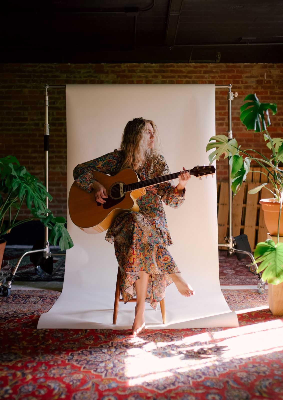 a woman holding a guitar standing in front of a white backdrop