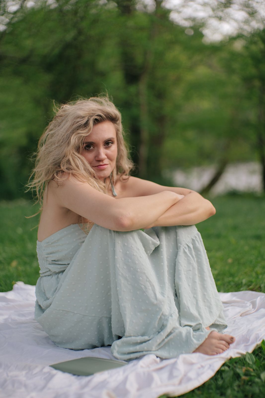 a woman sitting on a blanket in a park