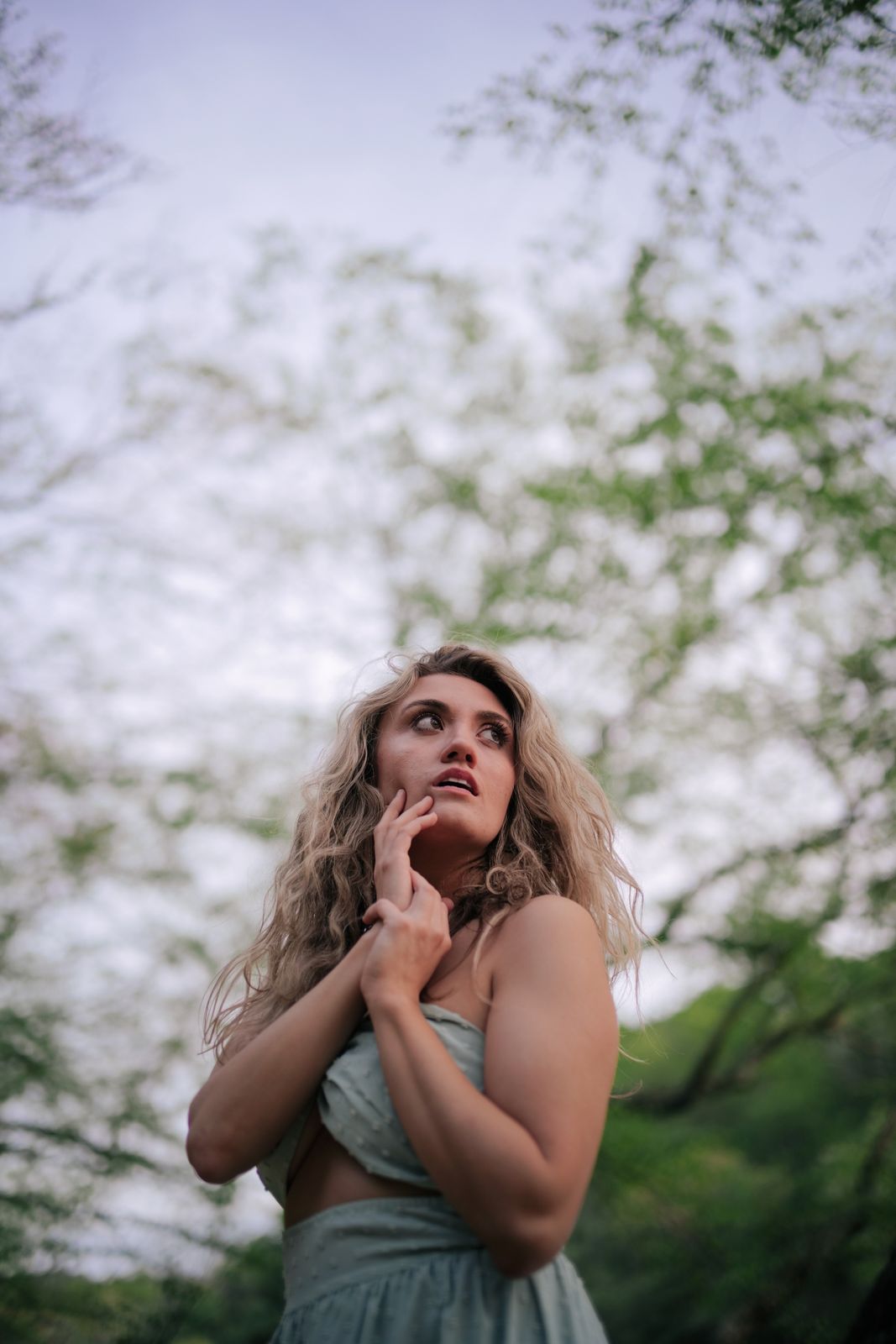 a woman in a green dress standing in front of a tree