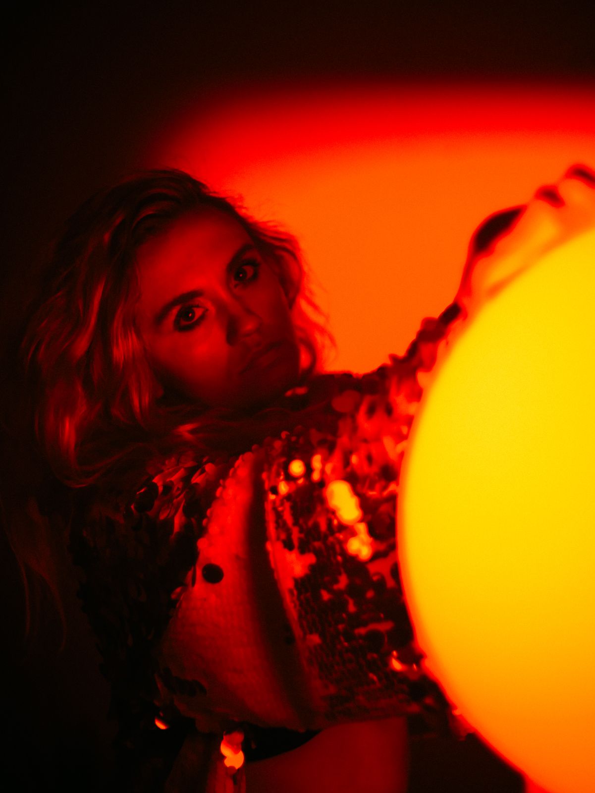 a woman holding a yellow ball in a dark room