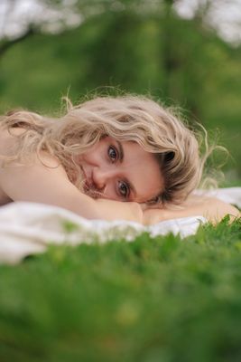 a woman laying on top of a lush green field