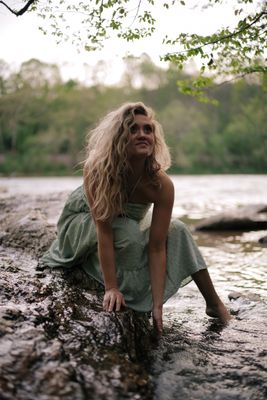 a woman sitting on a rock in the water