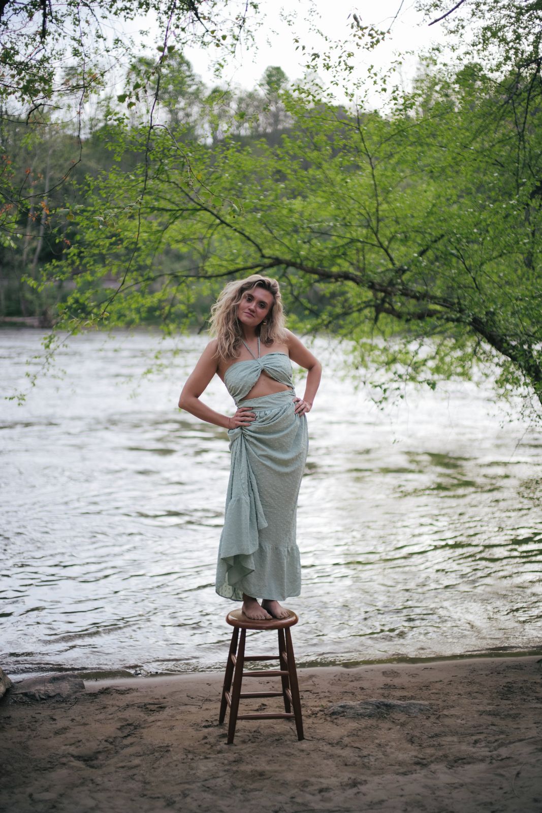 a woman standing on a stool next to a river