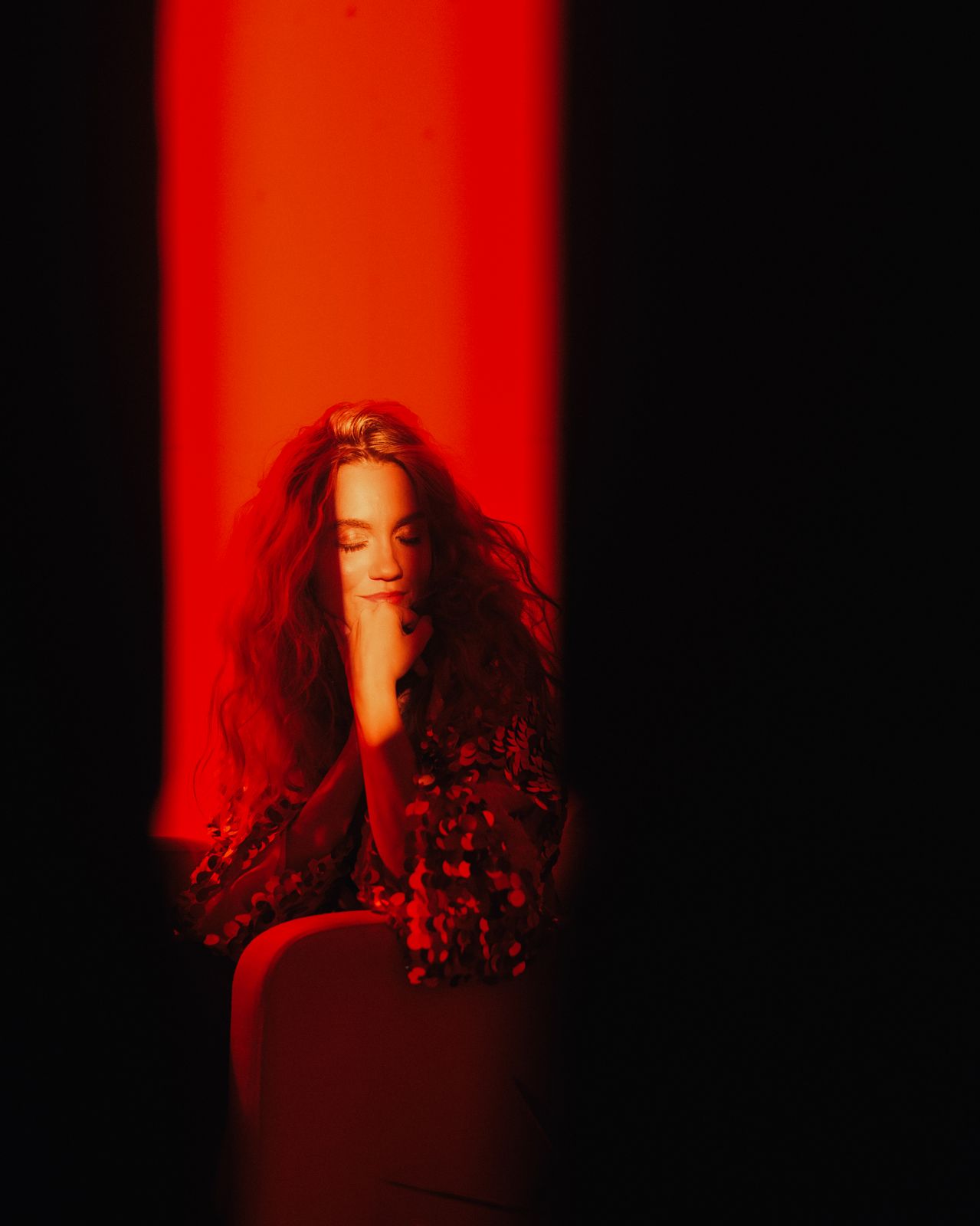 a woman sitting in a chair with her hand on her face