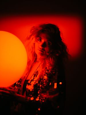 a woman holding a large orange ball in a dark room