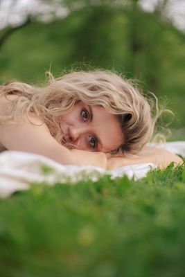 a woman laying on top of a lush green field