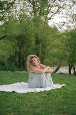 a woman sitting on a blanket in the grass