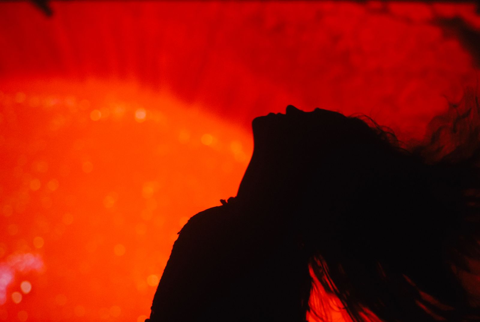 a silhouette of a woman with her hair blowing in the wind