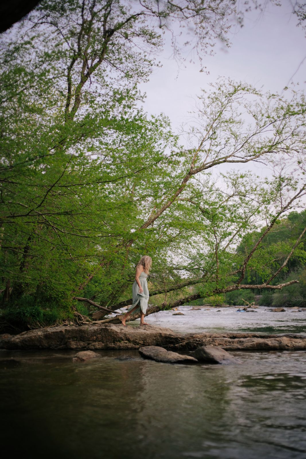 a woman standing on a log over a river