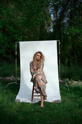 a woman sitting on a chair in front of a white backdrop