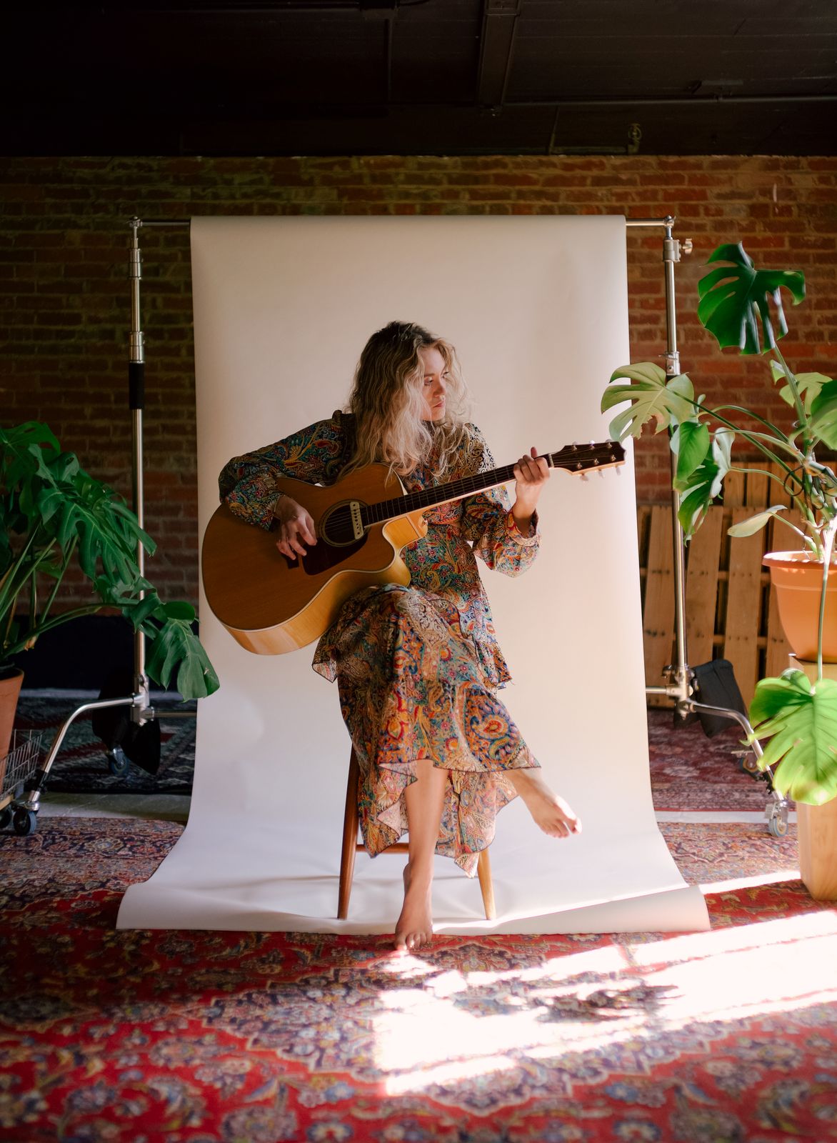 a woman playing a guitar in front of a white backdrop