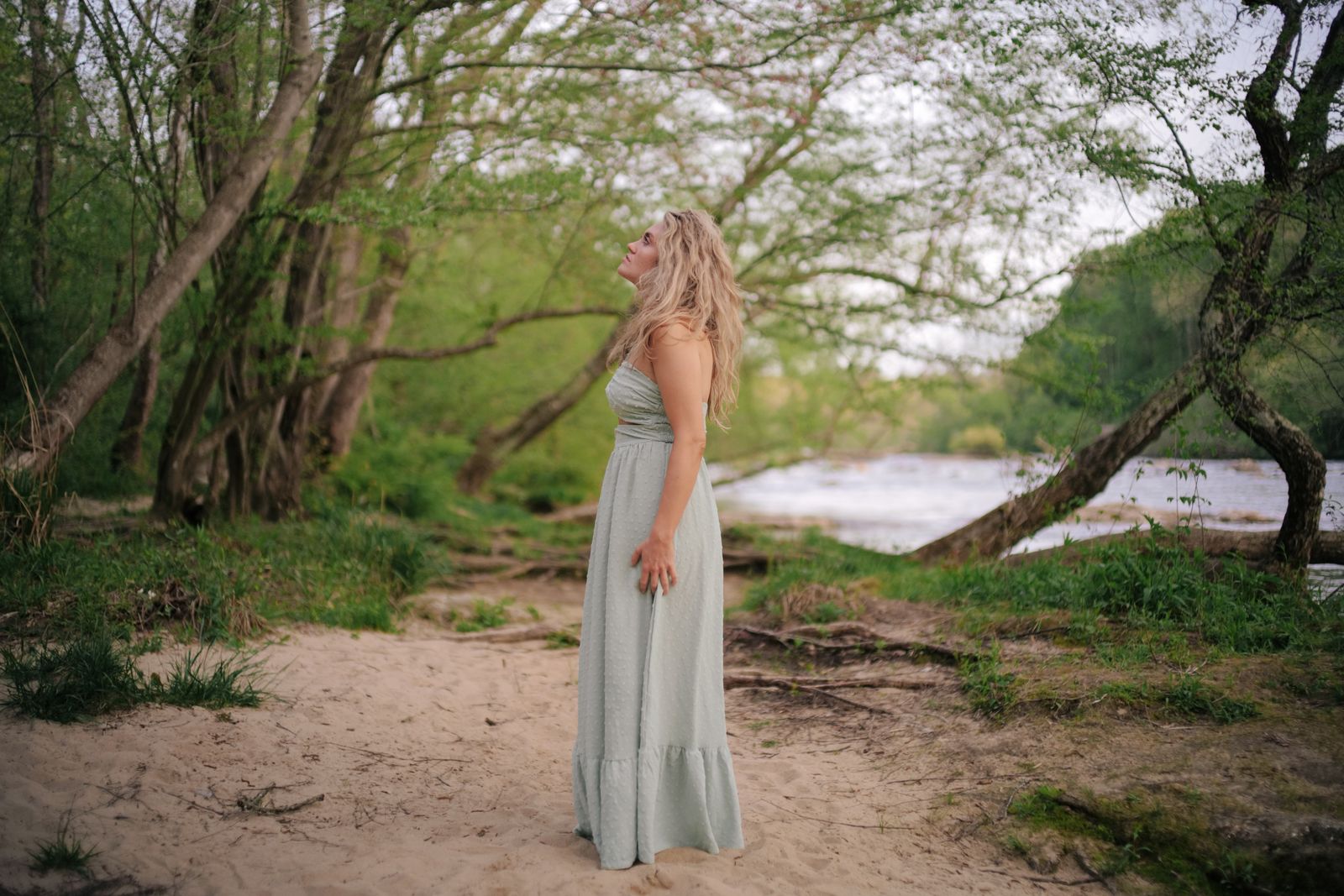 a woman in a long dress standing on a beach