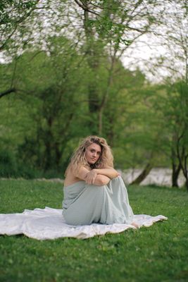 a woman sitting on a blanket in a park