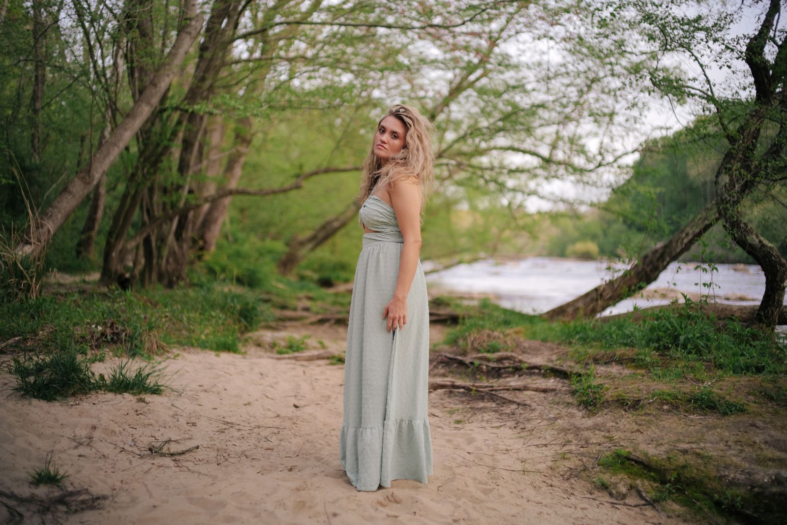 a woman in a long dress standing on a beach