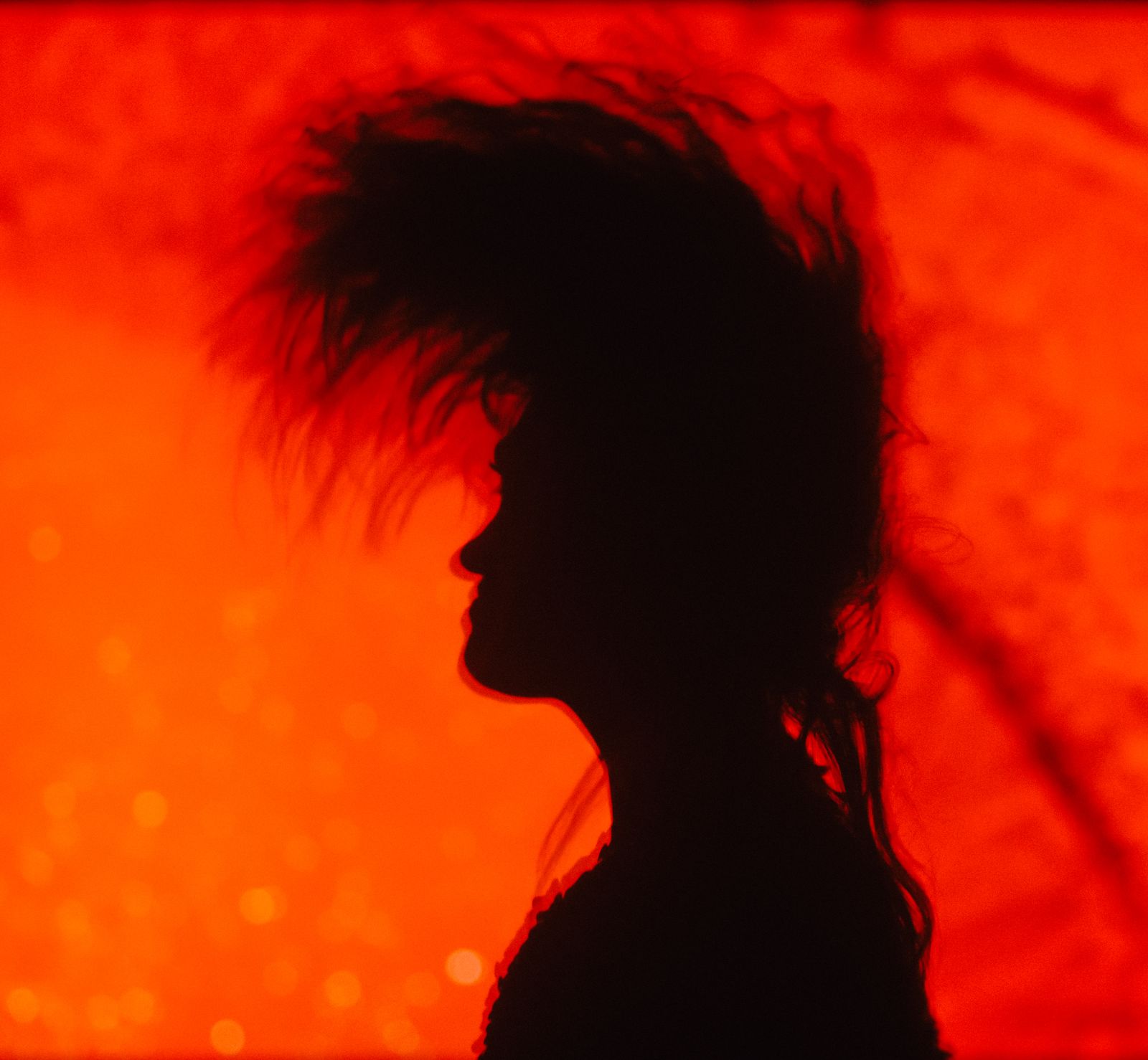 a silhouette of a woman with her hair blowing in the wind