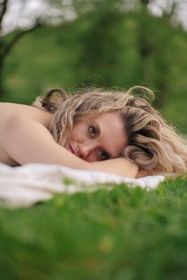 a woman laying on top of a lush green field