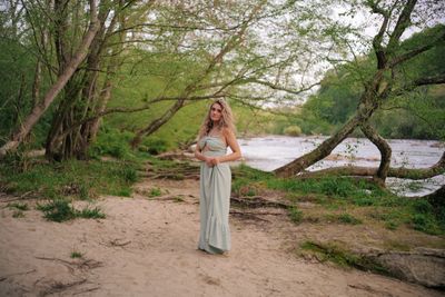 a woman in a long dress standing on a beach