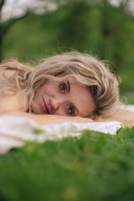 a woman laying on top of a lush green field