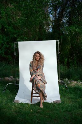 a woman sitting on a chair in front of a white backdrop