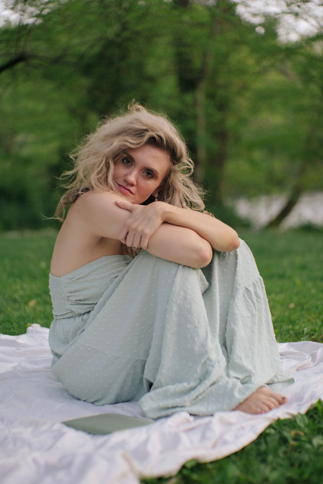 a woman sitting on a blanket in the grass