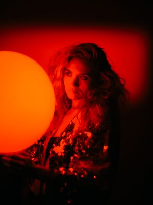 a woman holding a large orange ball in a dark room