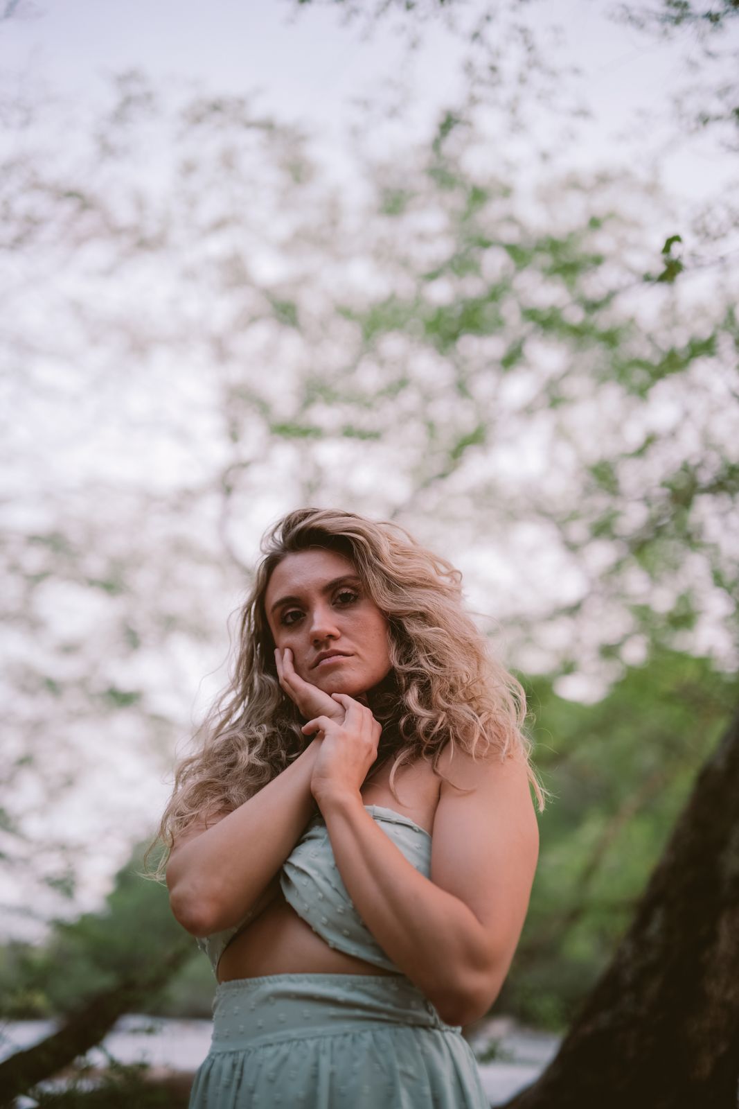 a woman in a green dress standing in front of a tree