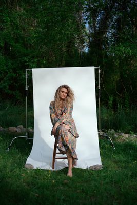 a woman sitting on a chair in front of a white backdrop