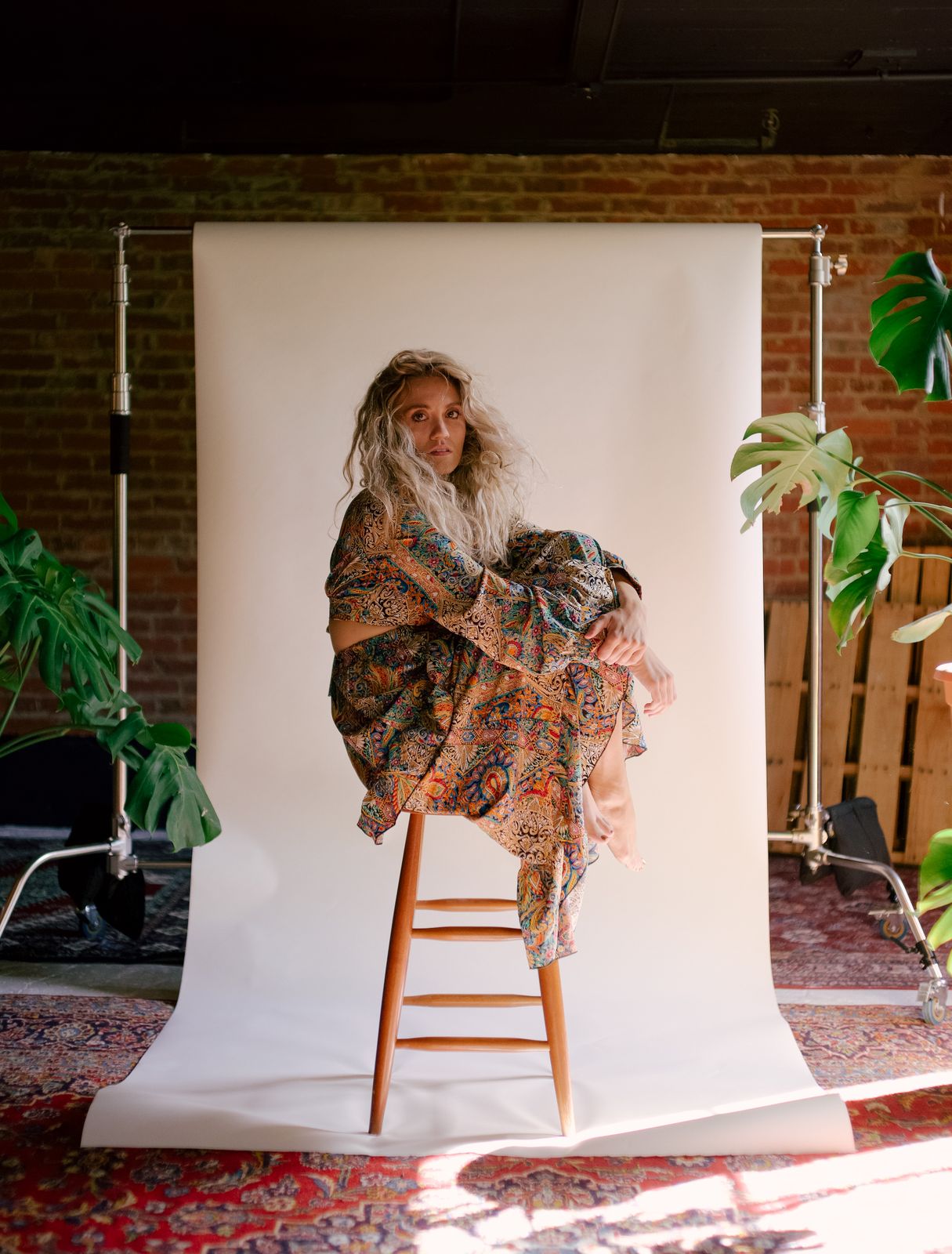 a woman sitting on a chair in front of a white backdrop