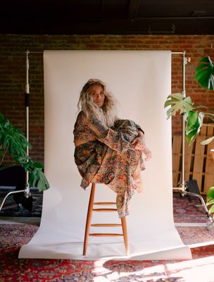 a woman sitting on a chair in front of a white backdrop