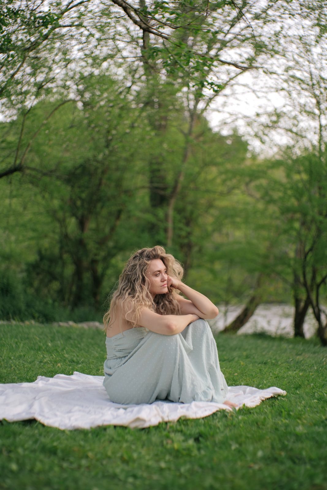 a woman sitting on a blanket in a park