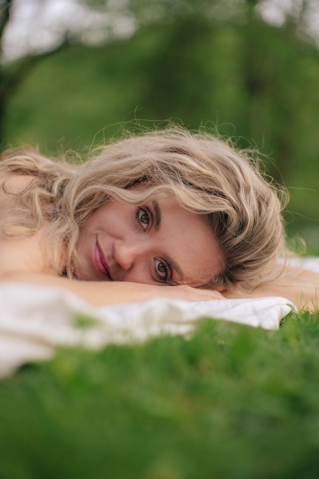 a woman laying on top of a lush green field