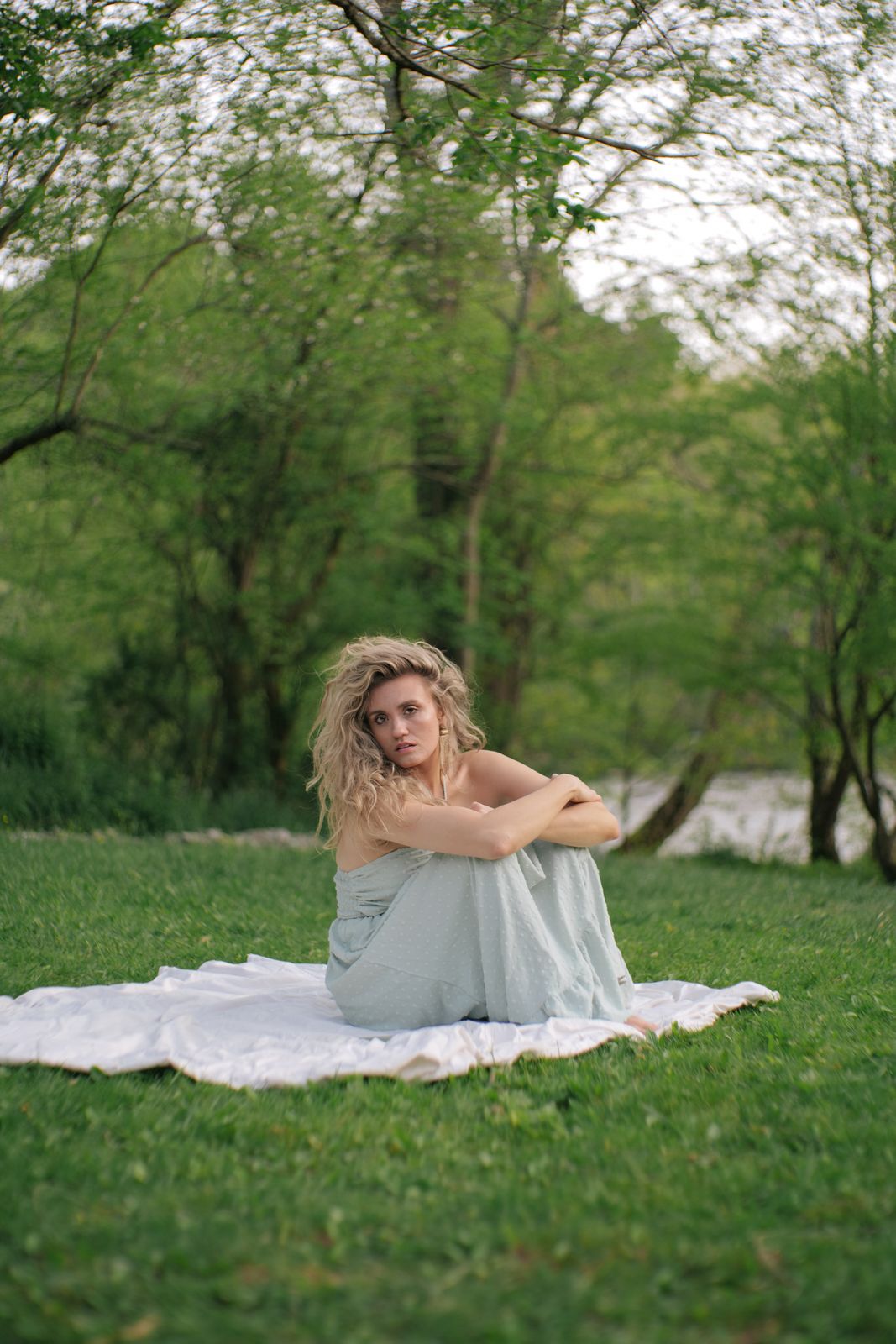 a woman sitting on a blanket in the grass