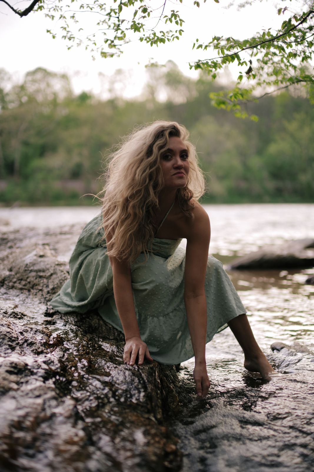 a woman sitting on a rock in the water