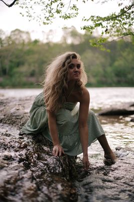 a woman sitting on a rock in the water