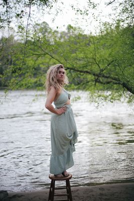 a woman standing on a stool in front of a river