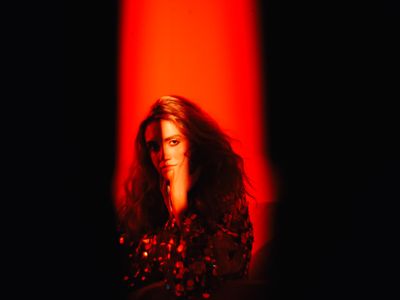 a woman with long hair standing in front of a red light