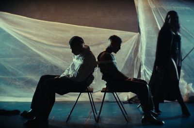 a man and a woman sitting on chairs in front of a curtain