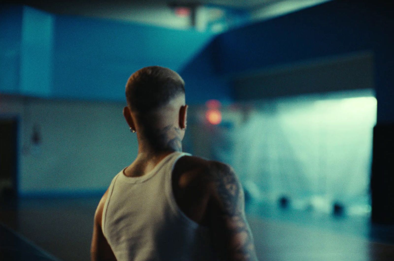 a man in a white tank top standing in a gym