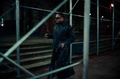 a man in a black coat and sunglasses walking down a street