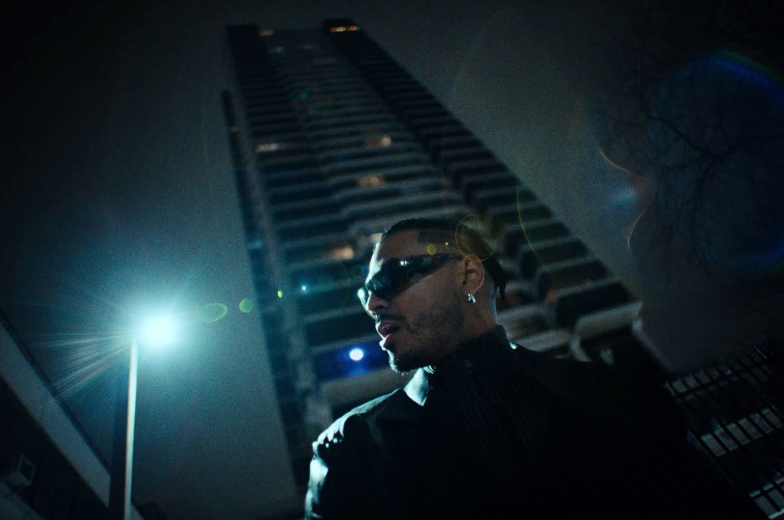 a man wearing sunglasses standing in front of a tall building