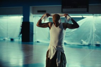 a man standing in a gym holding a towel over his head