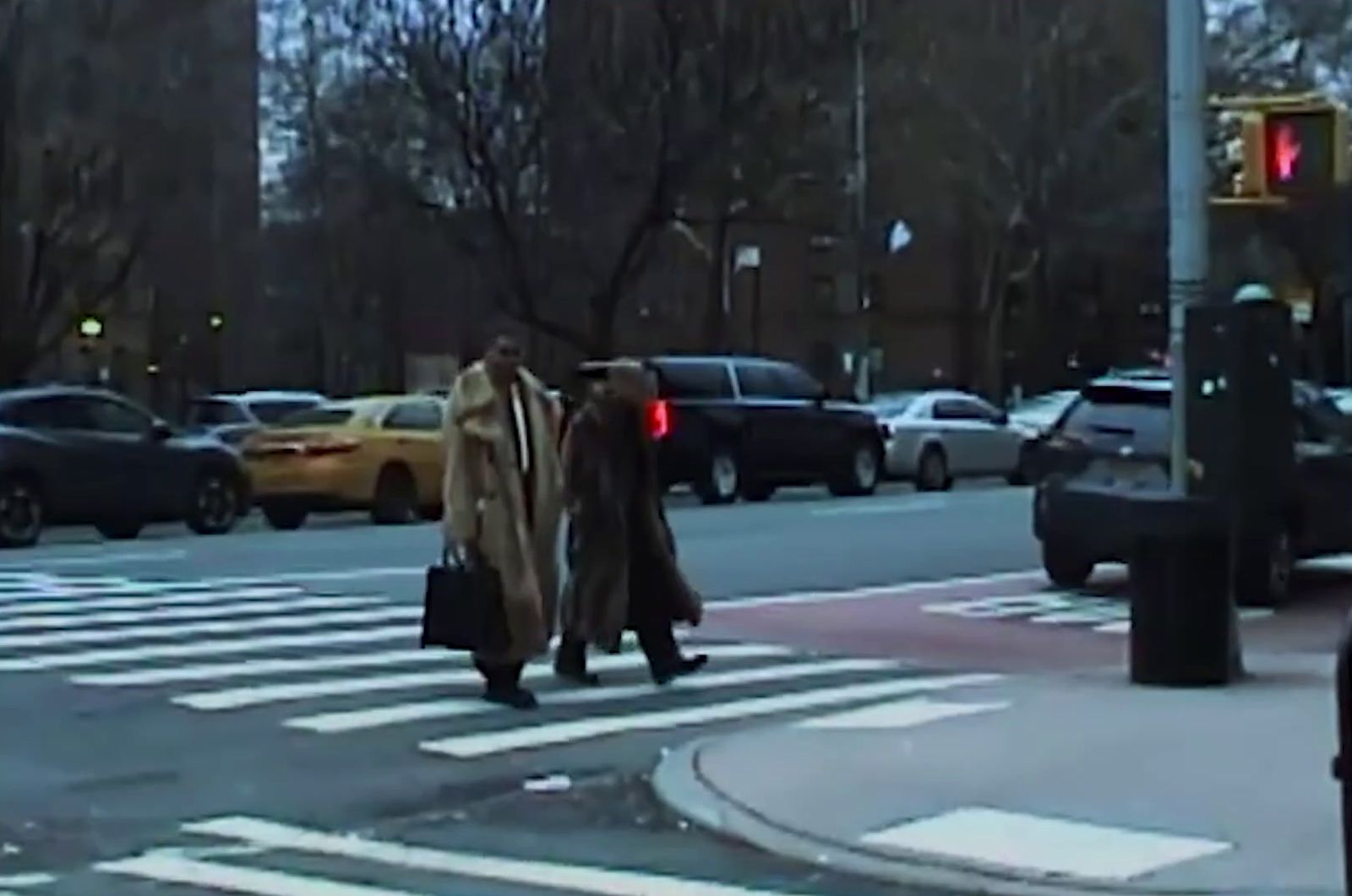 a man walking across a street holding a suitcase